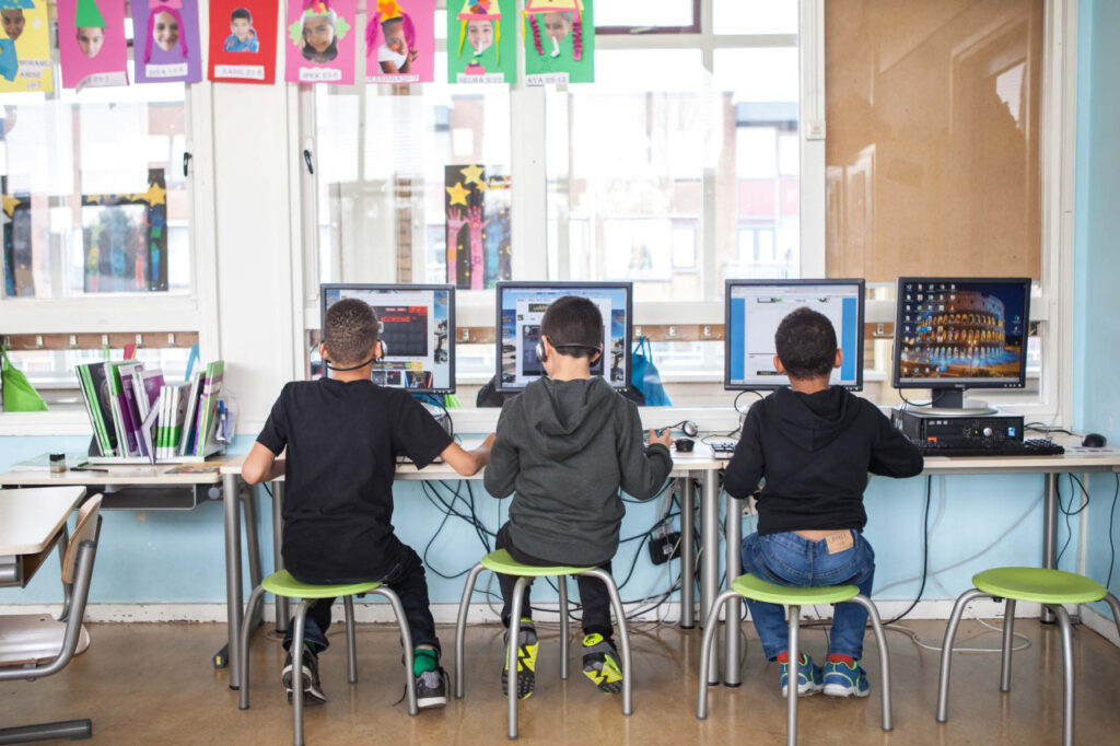 drie jongetjes zitten op school achter een pc