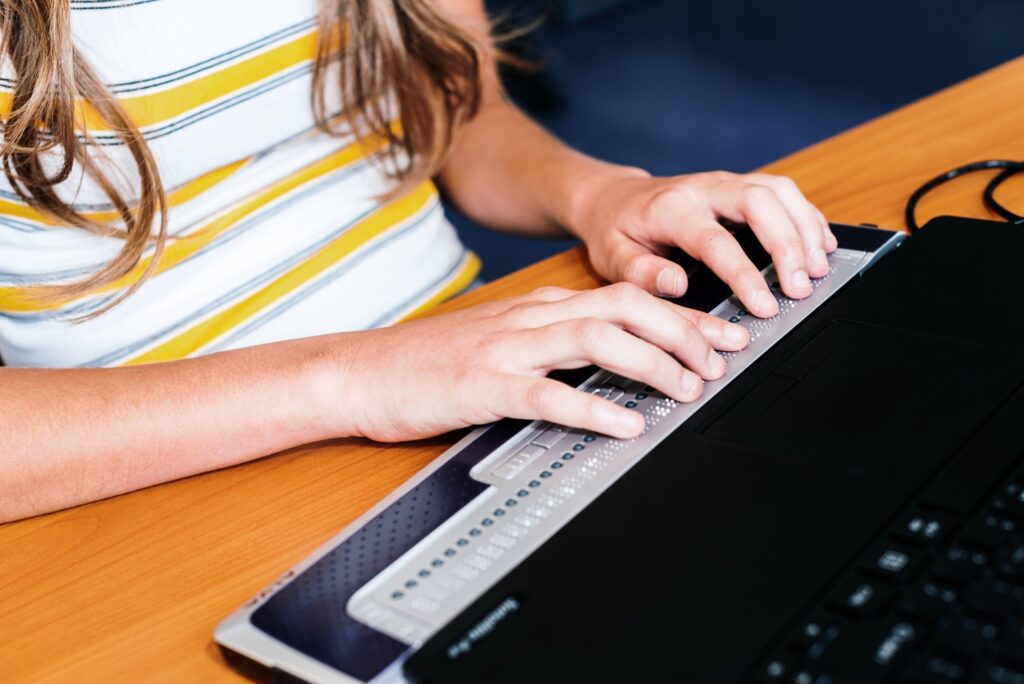 Close-up van kinderhanden die een brailleleesregel bedienen