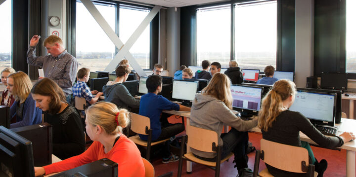 Een klas vol leerlingen die elk aan een computer zitten
