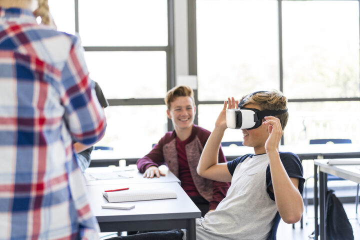 Een leerling in de klas draagt een VR-bril, andere leerlingen kijken toe